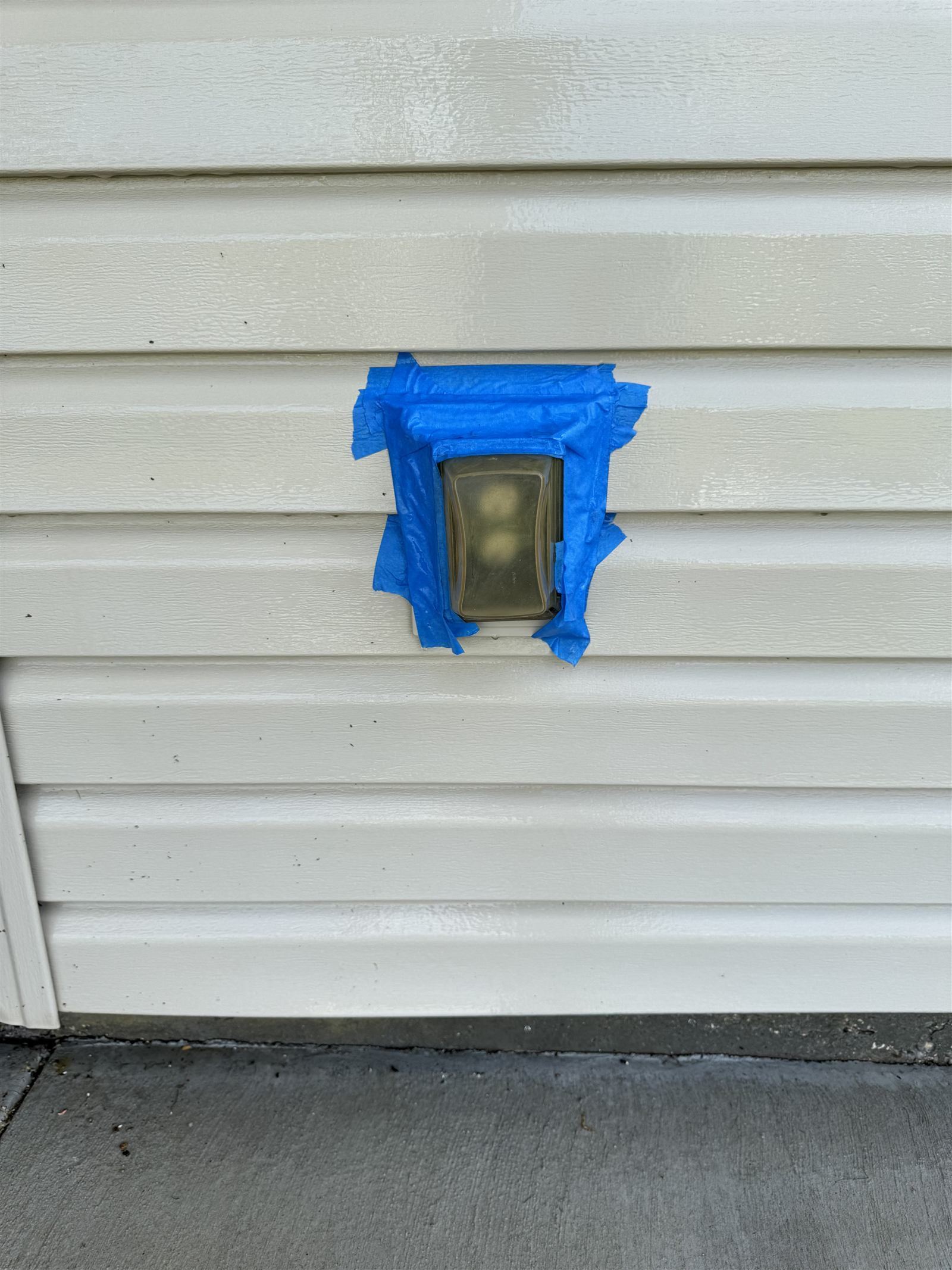 Exterior electrical outlet sealed with blue painter's tape before soft wash