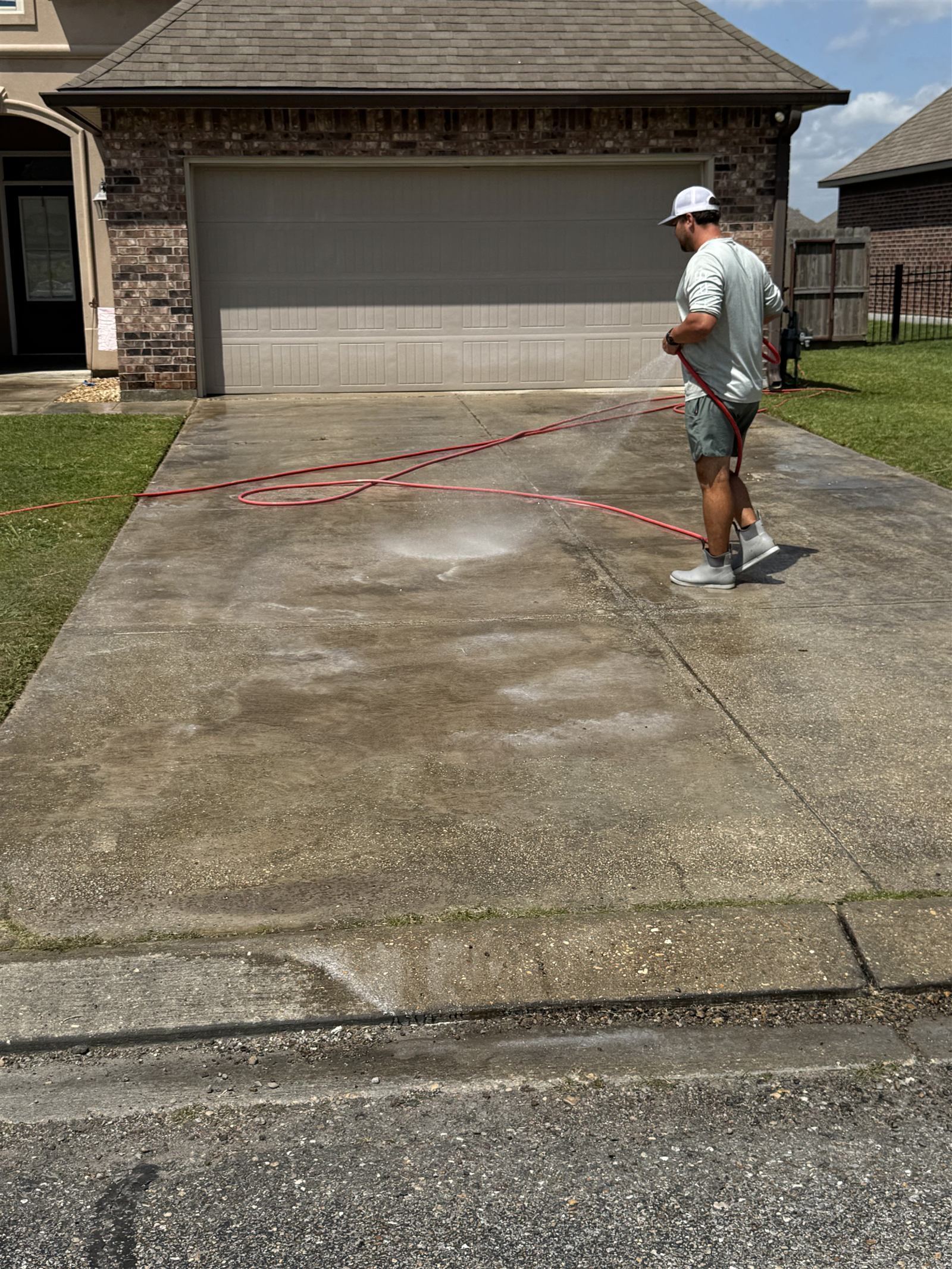 Driveway pressure washing — dramatic clean line visible